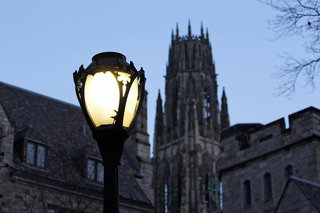 A lamp shines in the darkness as the sun sets on Yale's campus