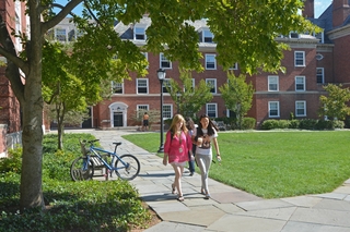 Two students walk down pathway at Silliman College during late summer