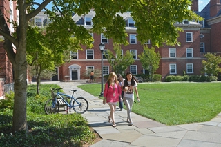 Two students walk down pathway at Silliman College during late summer